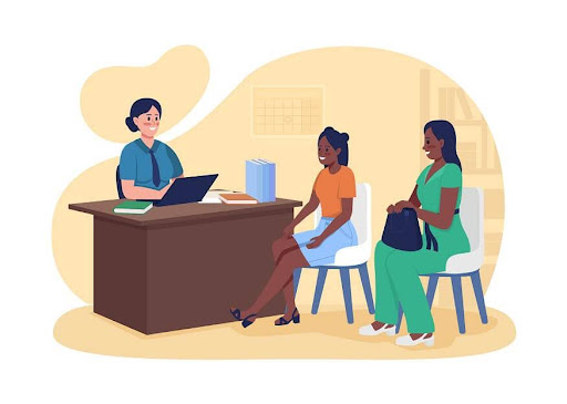 A person sitting across a table from two women, engaged in a conversation or discussion in a formal or casual setting.